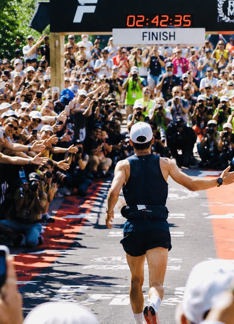 A runner approaching a finish line surrounded by supporters
